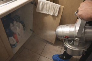 Technician removing Odor & musty smell from a damp cabinet area using professional odor removal equipment